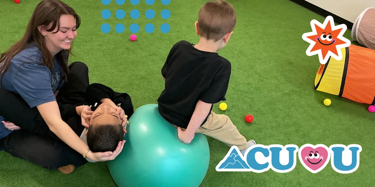 ACU therapist supporting a child during ABA therapy in the turf room